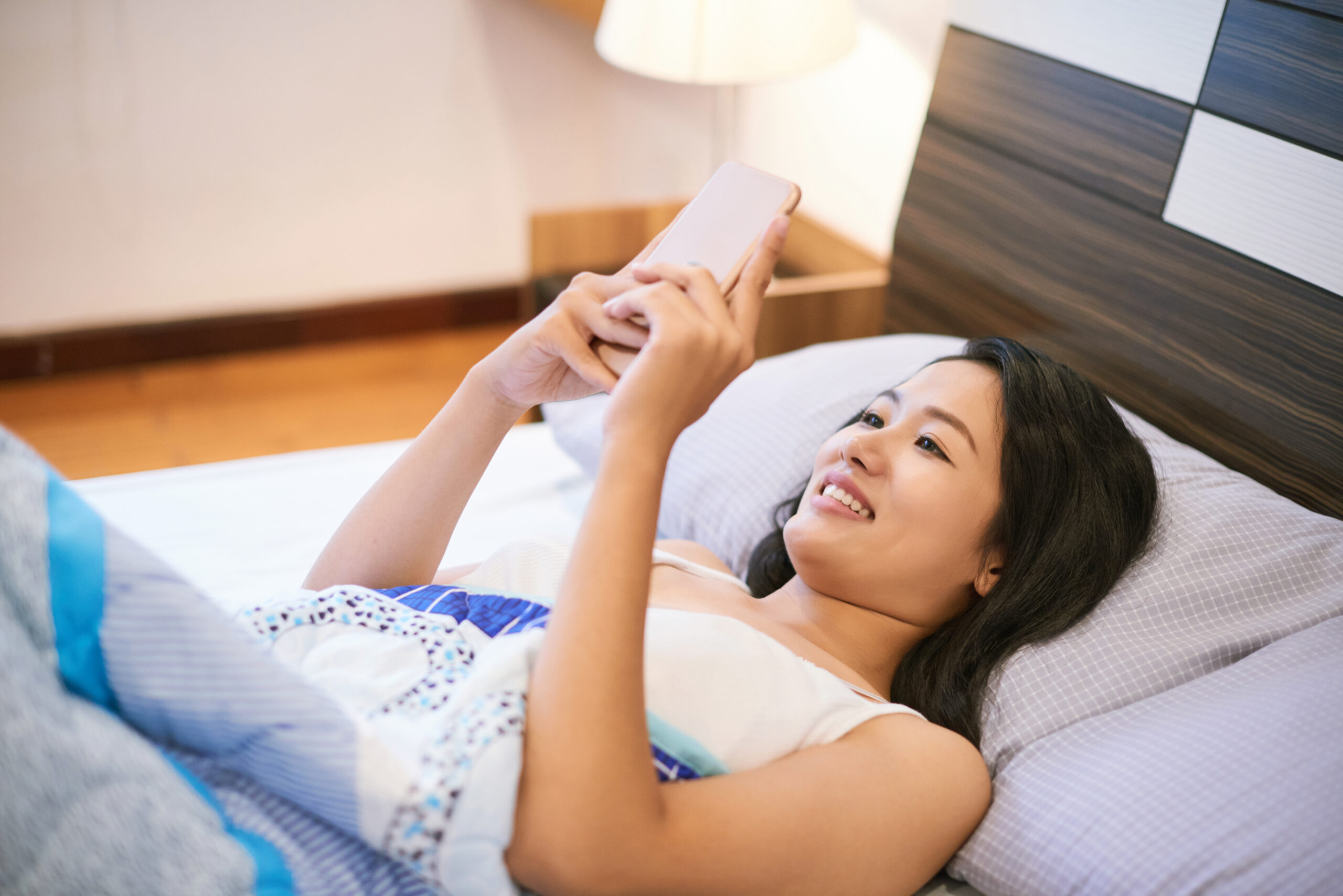 woman using phone in bed